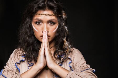 Portrait of a beautiful young brunette woman wearing tribal clothing and accessories standing...