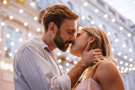 Image of amazing cute young loving couple walking by street outdoors kissing.の写真素材