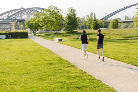 Image of two strong guys in sportswear working out and running at at green park outdoors in morning