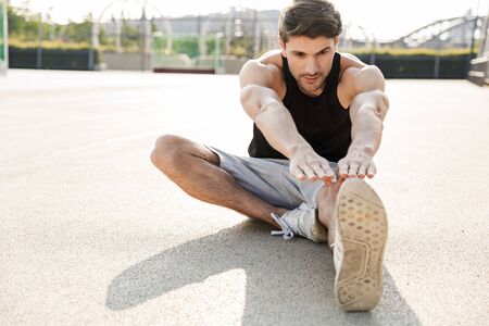 Image of muscular man in sportswear training on sports ground during morning workout outdoorsの写真素材