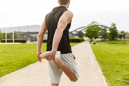 Photo of masculine man in sportswear working out and running at green park outdoors in morningの写真素材