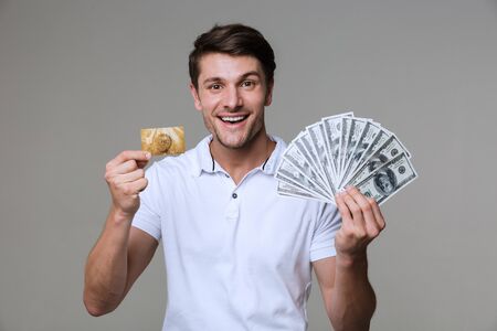 Image of a young happy positive optimistic man posing isolated over grey wall background holding...