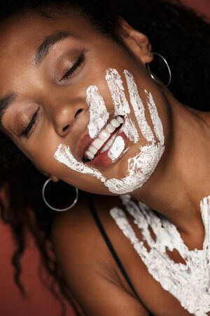 Close up portrait of an attractive smiling young african woman with white hand print on her face and...