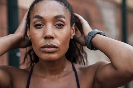 Close up of a confident young fit african sportswoman standing at the sportsgroundの写真素材