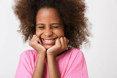 Cheerful funny little african girl wearing blouse standing isolated over white background, grimacing, laughingの写真素材