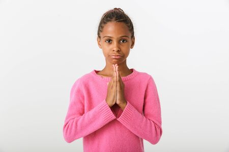 Image of unhappy african american girl standing and holding palms together isolated over white backgroundの写真素材