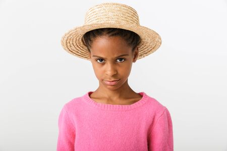 Image of serious african american girl in straw hat poising and looking at camera isolated over white backgroundの写真素材