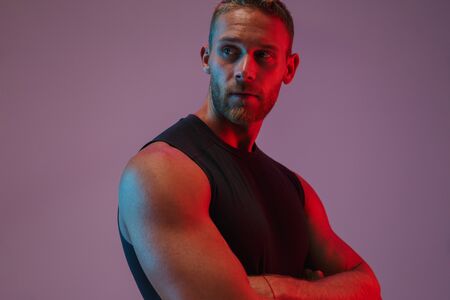 Portrait of a handsome fit muscular sportsman standing isolated over background, arms folded