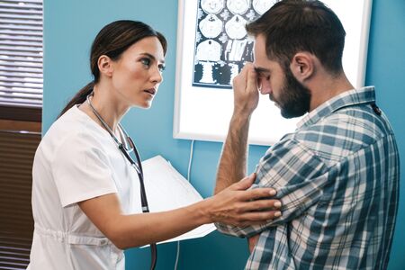 Image of female doctor in medical uniform and confused patient man looking at x-ray scan computed tomography results in hospitalの写真素材