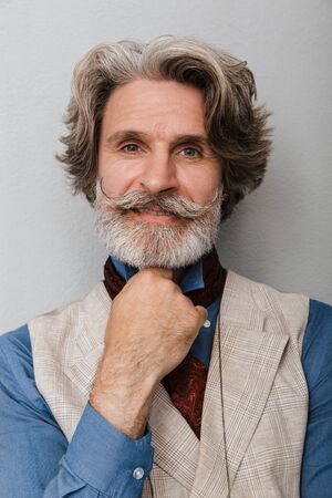 Image of a bearded pleased optimistic senior man grey hair isolated over grey wall background.の写真素材