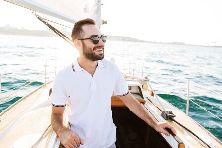 Image of a positive happy handsome young amazing man outdoors on yacht in sea.の写真素材