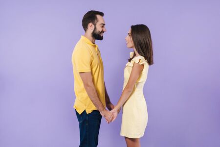 Happy excited beautiful young couple wearing casual clothing standing isolated over violet...