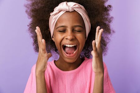 Image of a screaming happy young african girl kid posing isolated over purple wall background.の写真素材