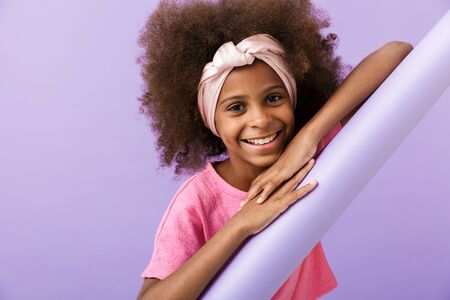 Image of a cheery young pleased african girl kid posing isolated over purple wall background.の写真素材