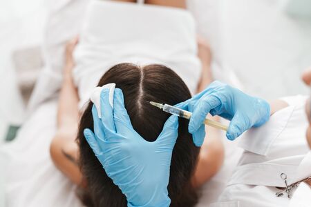 Photo of woman getting mesotherapy treatment in head for stimulation of growing hair by specialist in beauty salonの写真素材