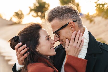 Image of a positive smiling optimistic beautiful adult loving couple walking outdoors near sea at the nature.の写真素材