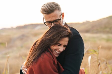 Image of a positive smiling optimistic beautiful adult loving couple walking outdoors at the nature hugging.の写真素材