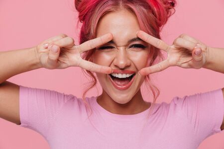 Portrait of caucasian woman with colorful hairstyle laughing and showing peace sign isolated over...