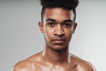 Photo closeup of shirtless african american man looking at camera while working out isolated over grey backgroundの写真素材