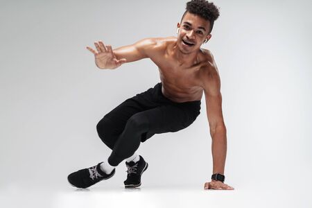 Photo of shirtless african american man using earpods and doing exercise while working out isolated...