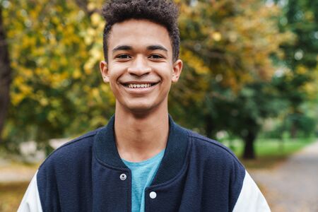 Cheerful african boy teenager walking at the park