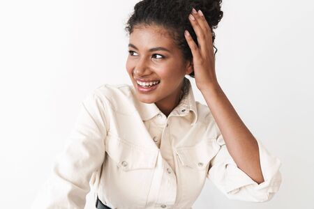 Beautiful smiling stylish young african woman standing over white background, posingの写真素材
