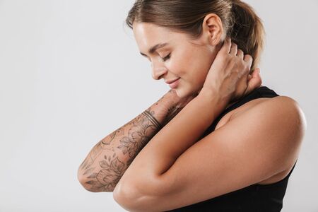 Image of attractive young woman in sportswear touching her neck while doing workout isolated over white backgroundの写真素材