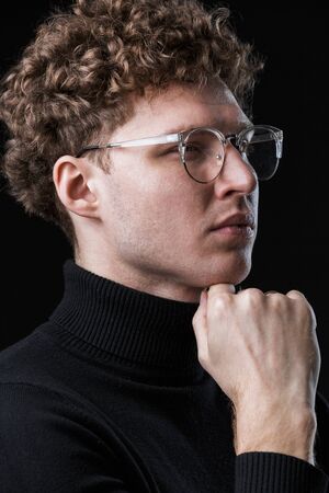 Close up of a handsome confident young curly haired businessman wearing turtleneck standing infront...