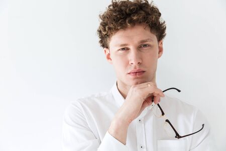 Close up of a handsome confident young curly haired businessman wearing white shirt standing infront...