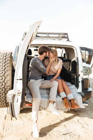 Image of a positive pleased happy young amazing loving couple outdoors hugging in car at the beach...