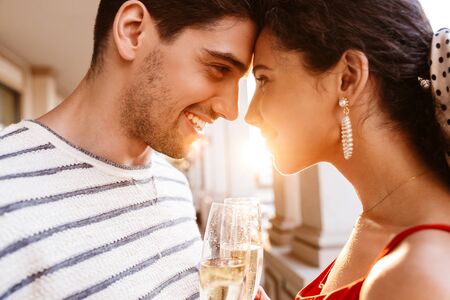Image closeup of happy young couple looking at each other and drinking champagne near colonnadesの写真素材