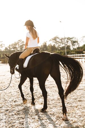 Image of caucasian young blonde beautiful woman wearing hat with horse in countryside outdoors