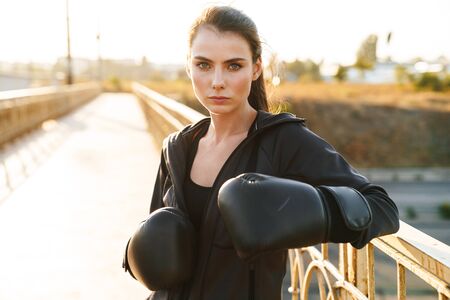Image of a sports fitness woman boxer in gloves outdoors make exercises.の写真素材