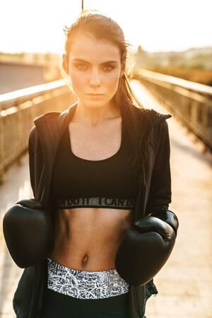 Image of a sports fitness woman boxer in gloves posing outdoors.の写真素材