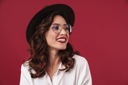 Photo of a cheerful happy young amazing woman posing isolated over red wall background.の写真素材