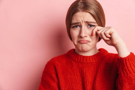 Image of sad negative young woman posing isolated over pink wall background.の写真素材