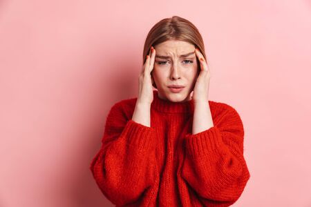 Photo of unhappy blonde woman with headache posing and looking at camera isolated over pink wallの写真素材