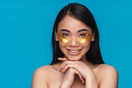 Photo of asian happy positive optimistic young woman posing isolated over blue wall background take...