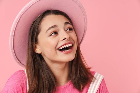 Photo of lovely charming girl in hat laughing and posing at camera isolated over pink backgroundの写真素材