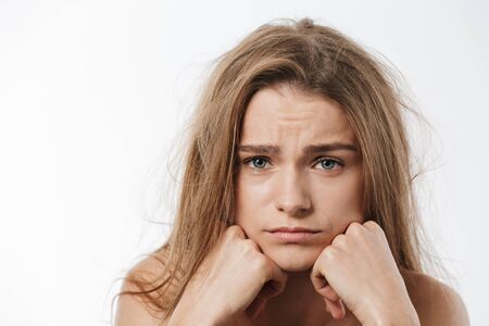 Beauty portrait of gorgeous young blonde half-naked woman being upset with her messy hair isolated...