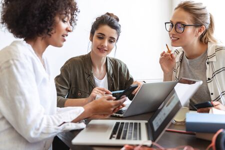 Group of multiethnic cheerful young women studying together at the coffee shop