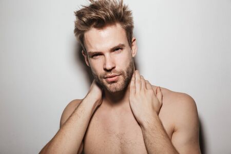 Handsome shirtless seductive young man posing isolated over white background, looking at cameraの写真素材