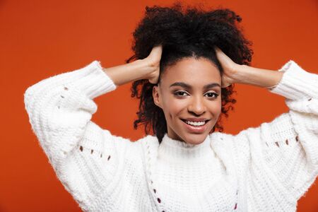 Beautiful cheerful young african woman wearing sweater standing islolated over red background,...