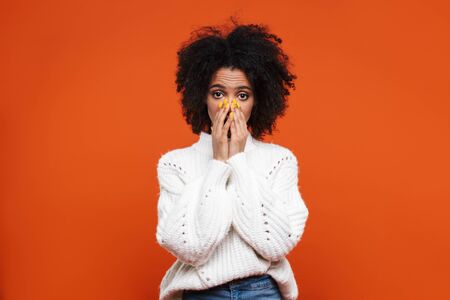 Shocked young attractive african woman looking at camera isolated over red background