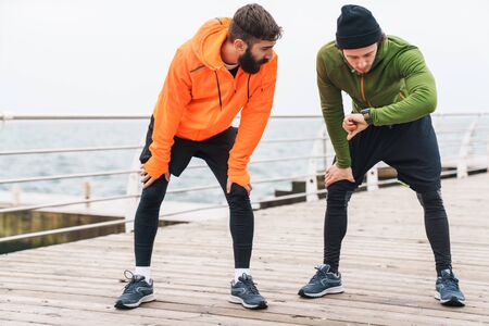 Two motivated young sportsmen exercising outdoors at the seaside, joggingの写真素材
