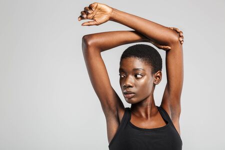 Image of athletic african american woman stretching her arms while working out isolated over white backgroundの写真素材