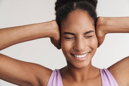Portrait of african american funny woman laughing and covering her ears isolated over white backgroundの写真素材