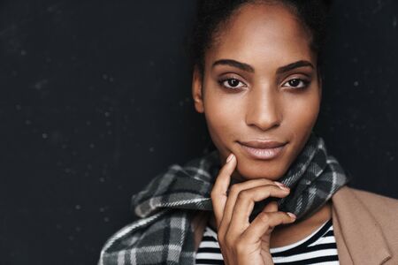 Portrait of african american seductive woman posing and looking at camera isolated over black wall