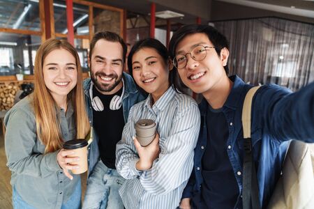 Photo of multinational cheerful students laughing while taking selfie photo in classroomの写真素材