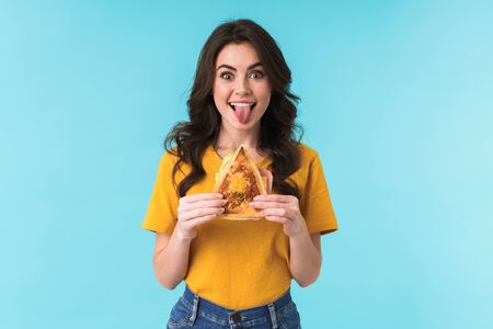 Photo of positive optimistic young beautiful woman posing isolated over blue wall background holding...